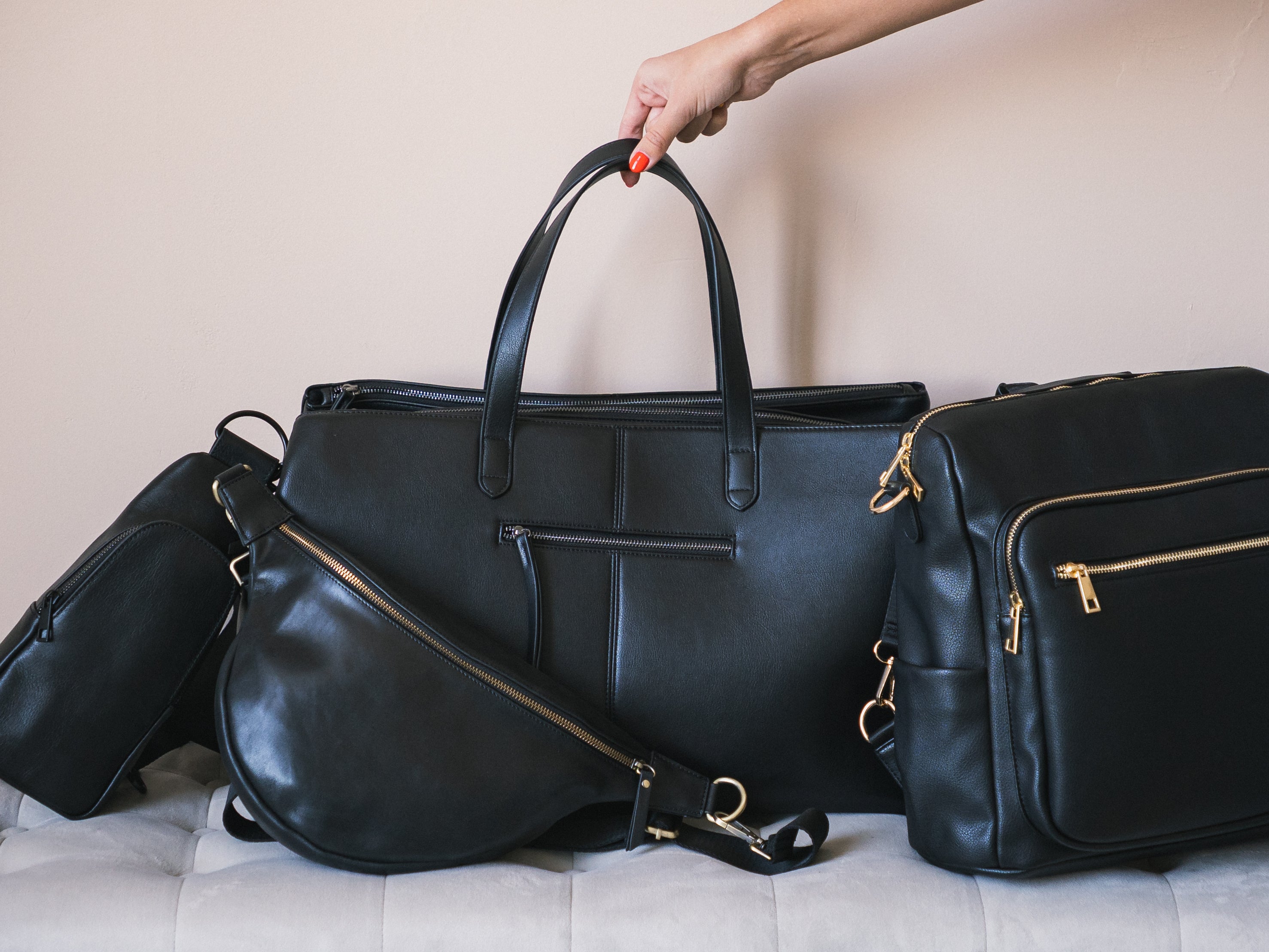 Minimalist black travel bag set from Pink Cove featuring a large weekender tote, structured backpack with gold zippers, and a sleek crossbody sling bag