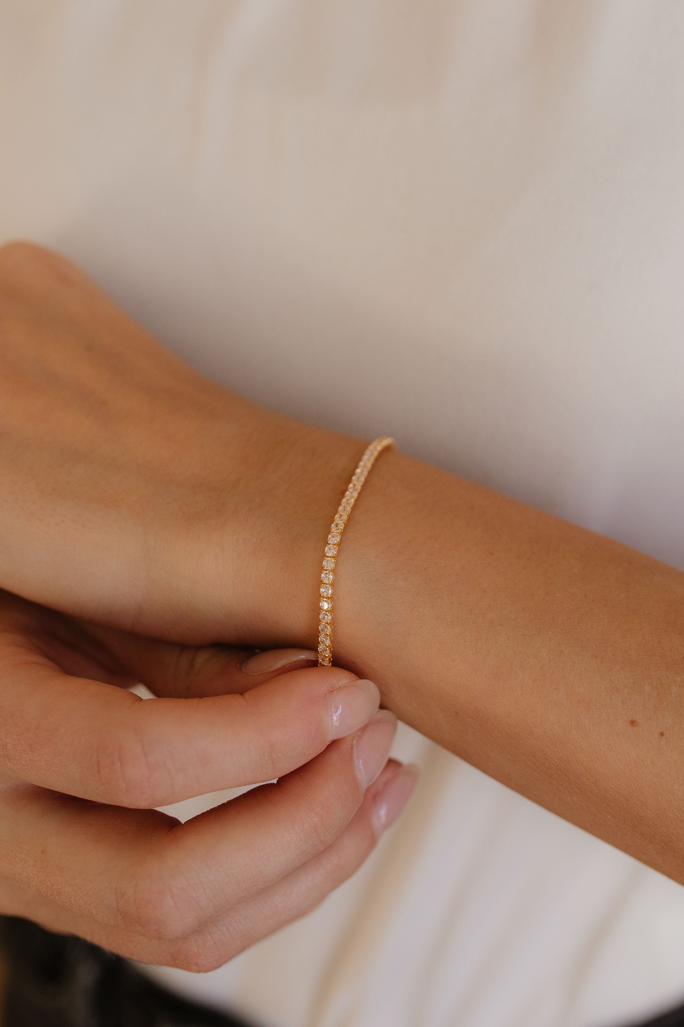 A woman's arm featuring a sleek gold and diamond bracelet from Pink Cove. 